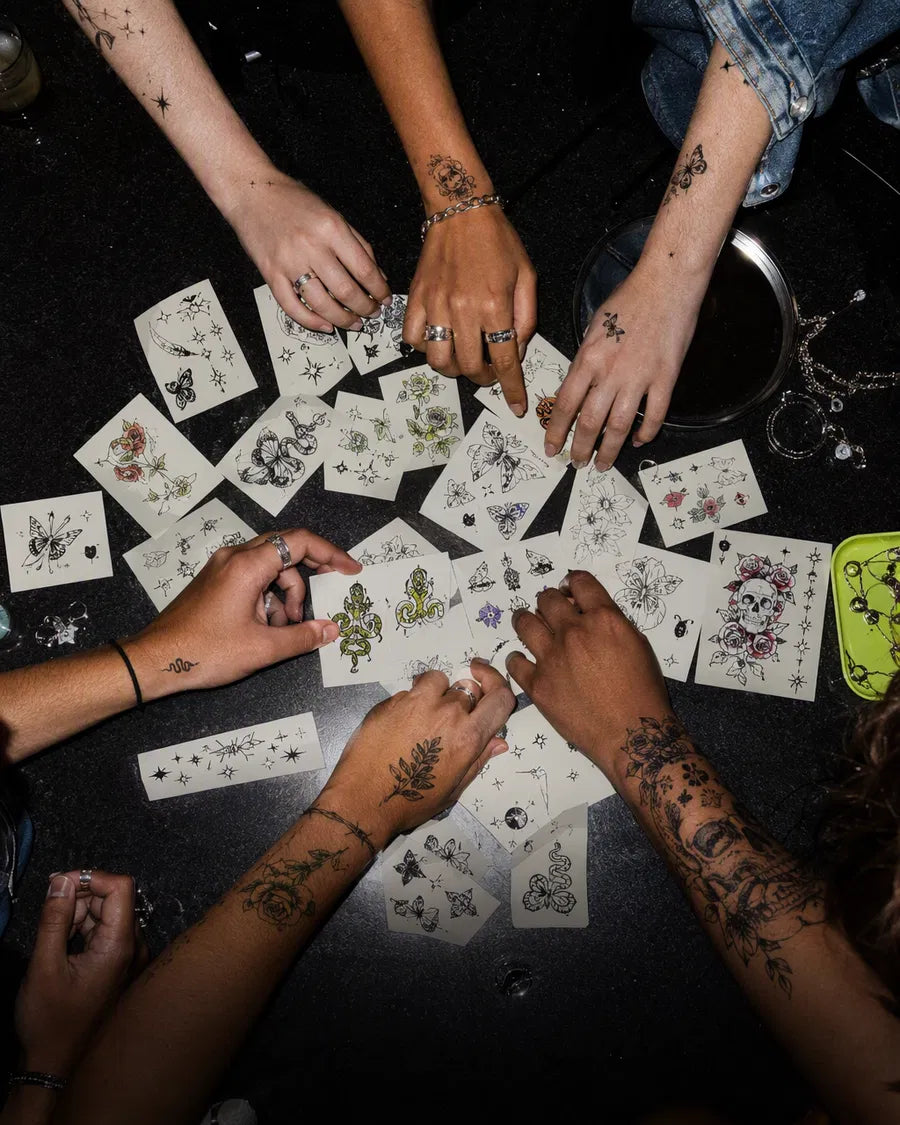 Friends choosing realistic temporary tattoo designs from a large collection